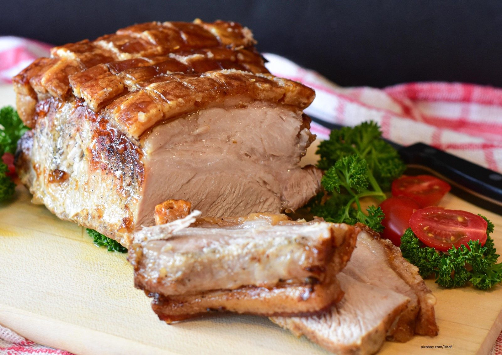 Angeschnittener Schweinebraten auf einem Holzbrett.