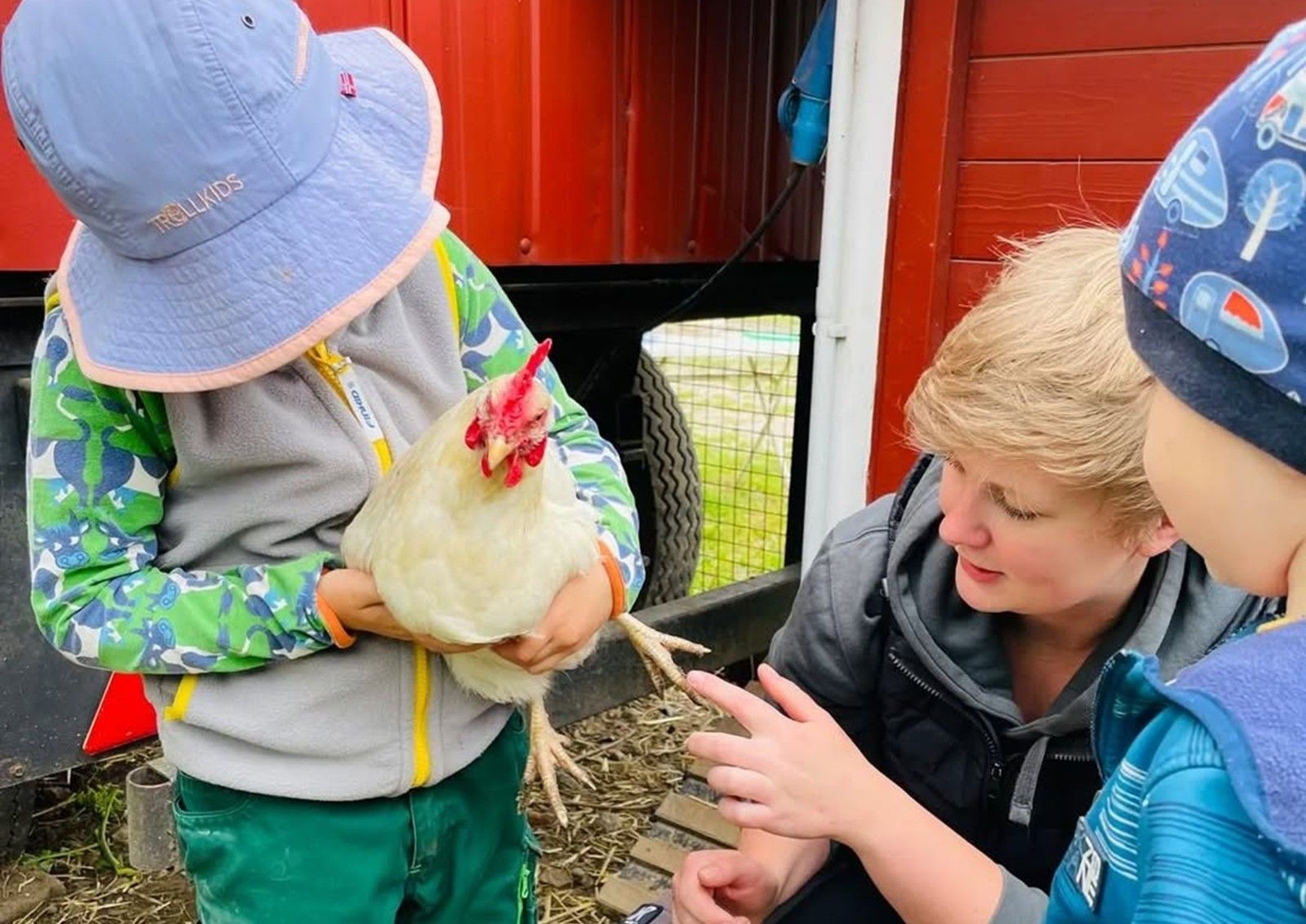 Charlotte Schlichting mit zwei Kindern, eines hält ein Huhn im Arm.